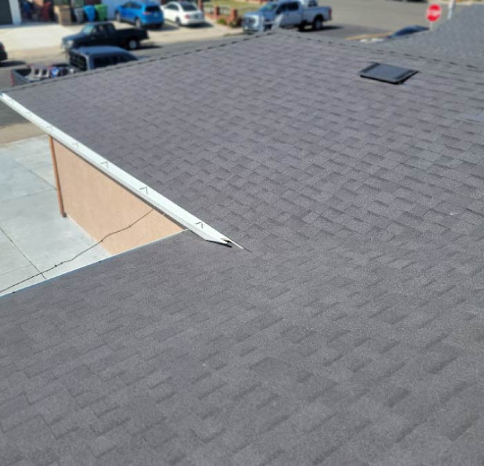An overhead view of a premium asphalt shingle roof replacement completed by New Concept Roofing Inc., showcasing charcoal grey architectural shingles, pipe boots, and crisp ridge caps