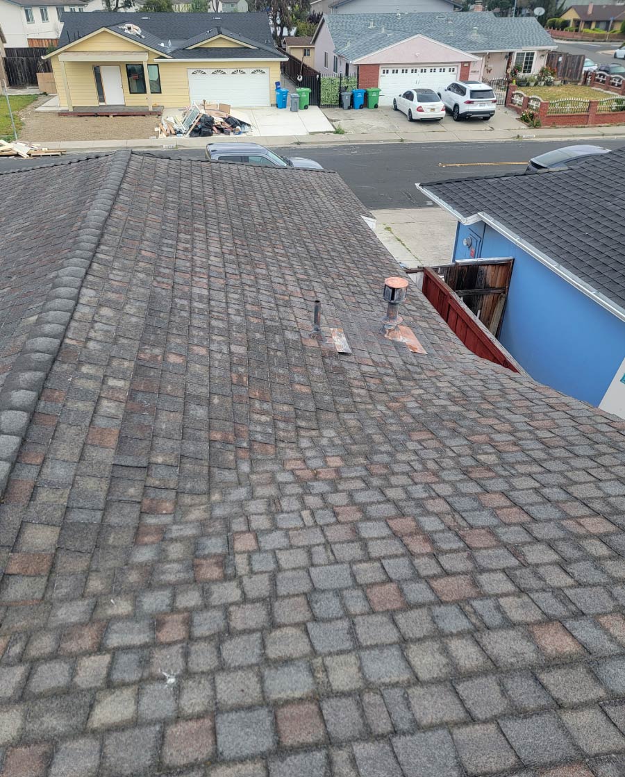 A worn, weathered, and multi-colored interlocking asphalt shingle residential roof displaying aging and discoloration prior to a full roof replacement by New Concept Roofing Inc.