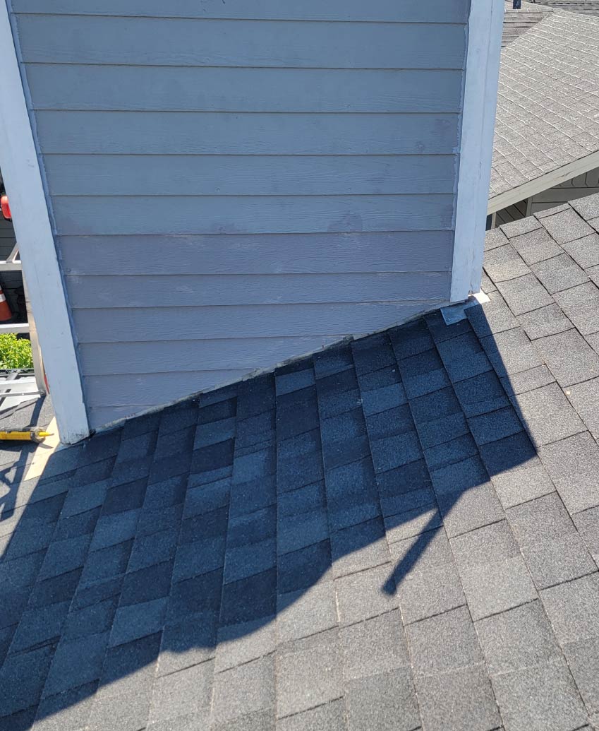 A professional roofer from New Concept Roofing Inc. performing precision roof repair on a residential asphalt shingle valley using specialized tools and high-quality materials under bright sunlight