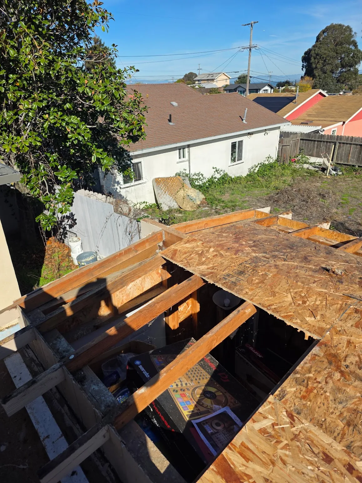 Roof replacement in progress showing exposed rafters and new decking installation 